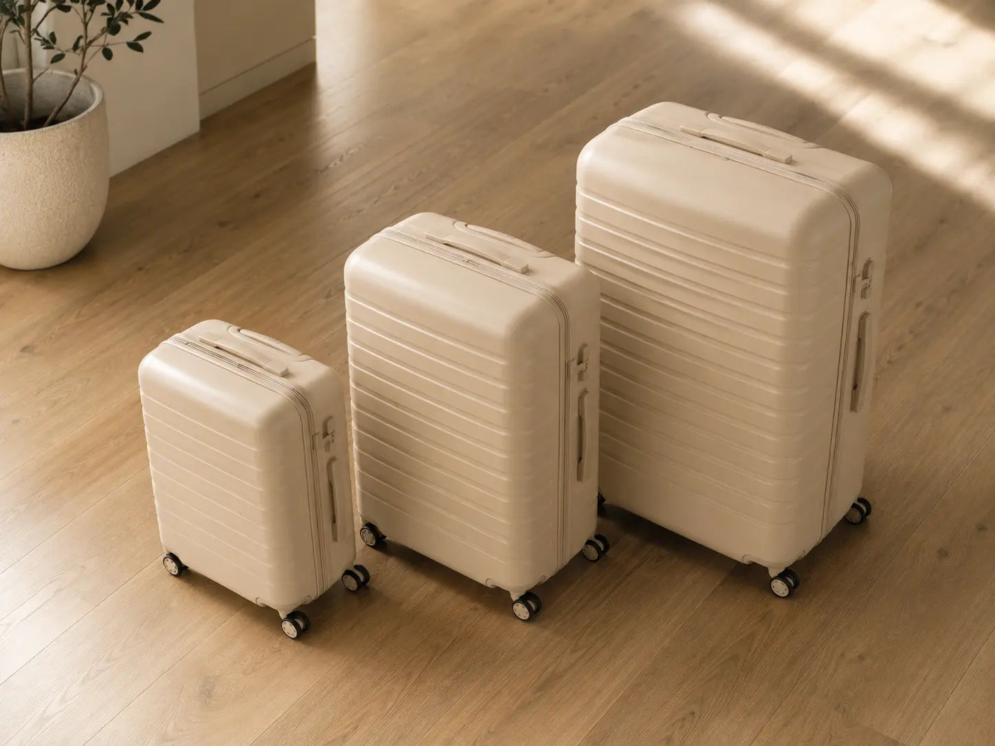 trois valises alignées de taille croissante S M L sur parquet clair