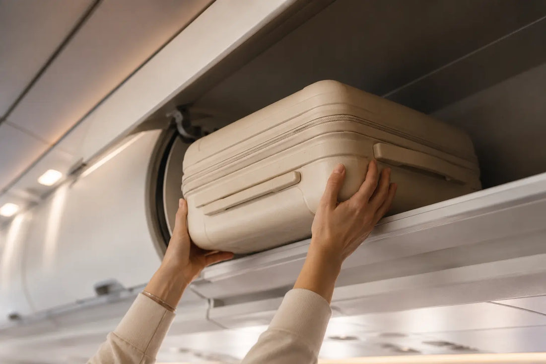 main glissant une valise compacte dans un casier overhead d'avion, lumière cabine