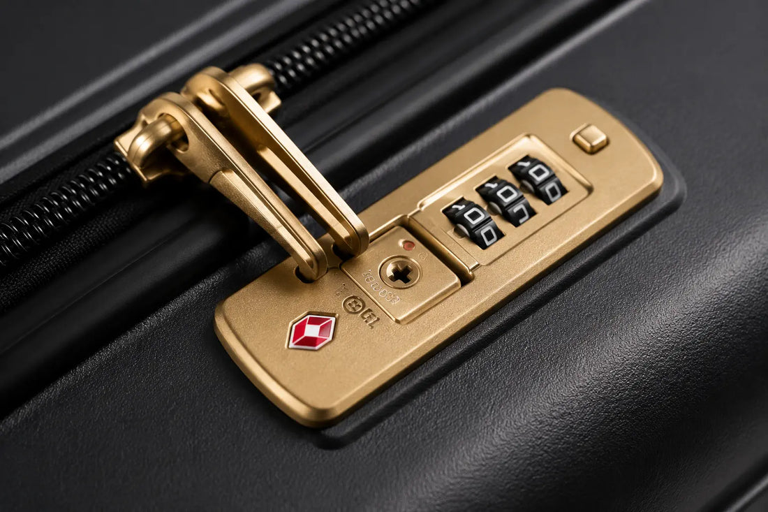 gros plan sur une serrure TSA dorée sur une valise noire, logo TSA visible